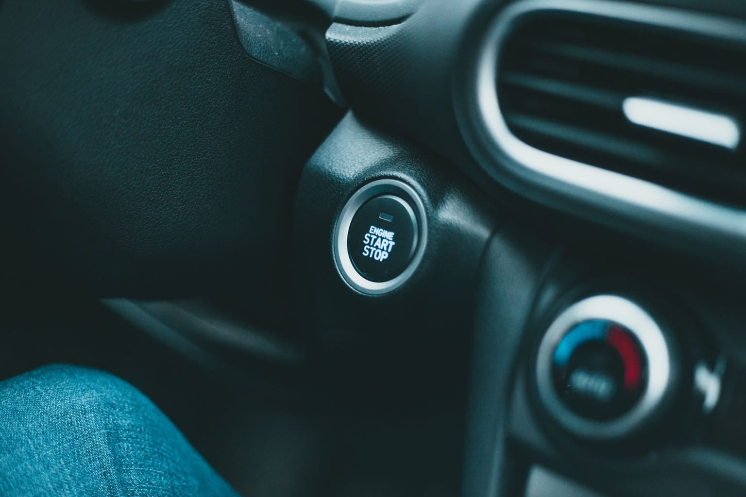 Engine start button on a car dashboard beside the air vents