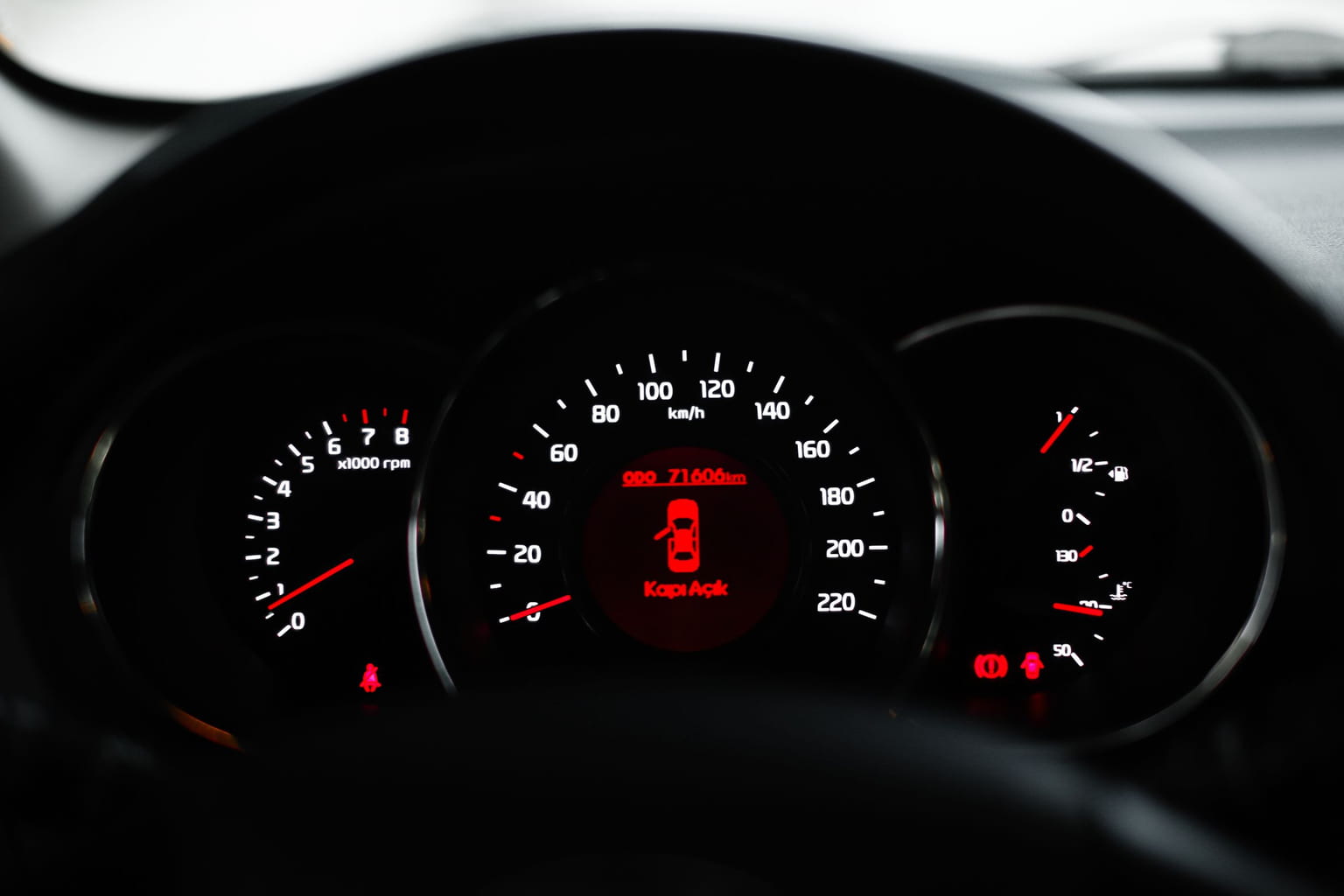 Car instrument cluster at night with red warning lights lit