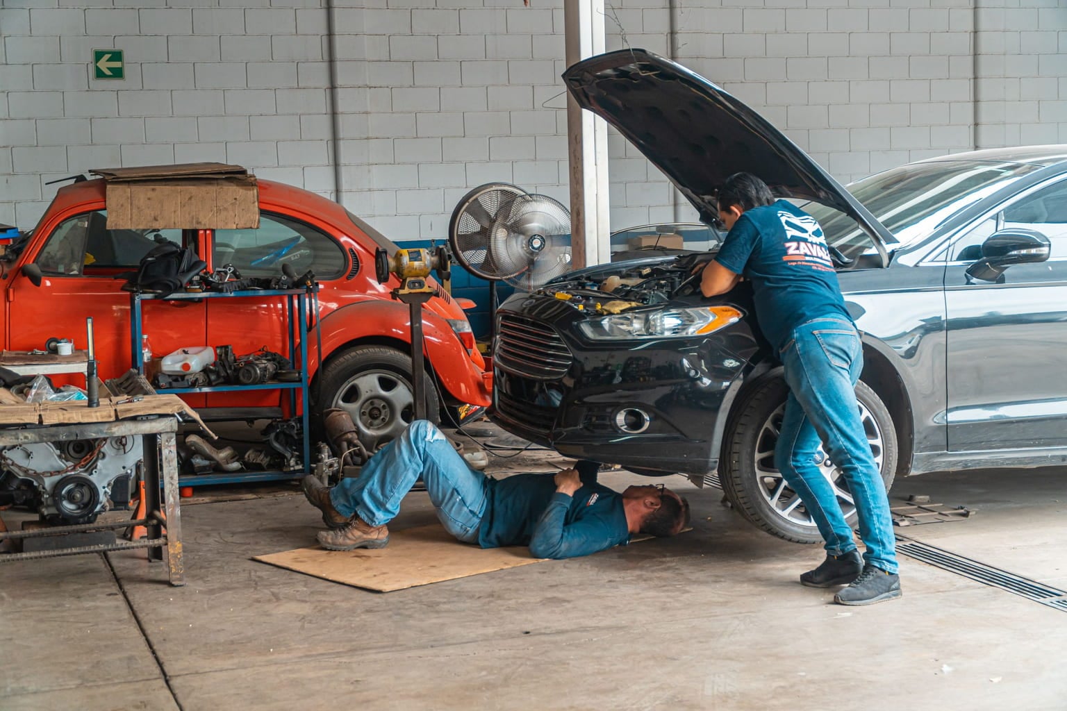 Two mechanics working on cars in an auto repair workshop