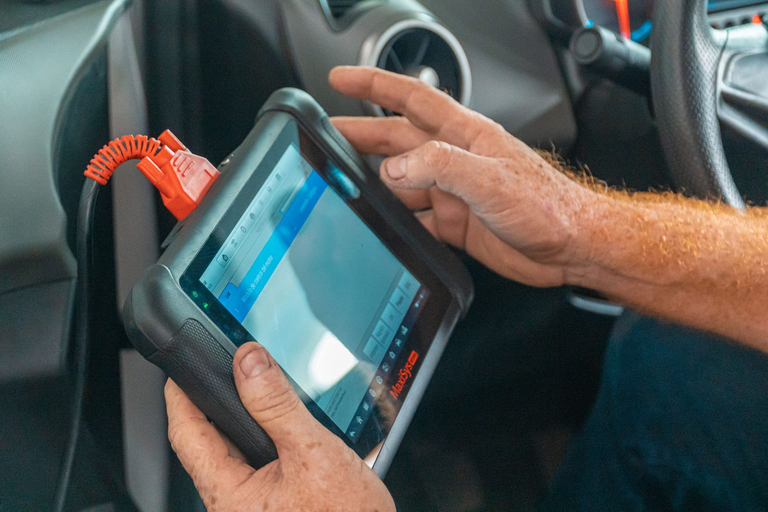 Mechanic reading engine data on a diagnostic tablet plugged into a car