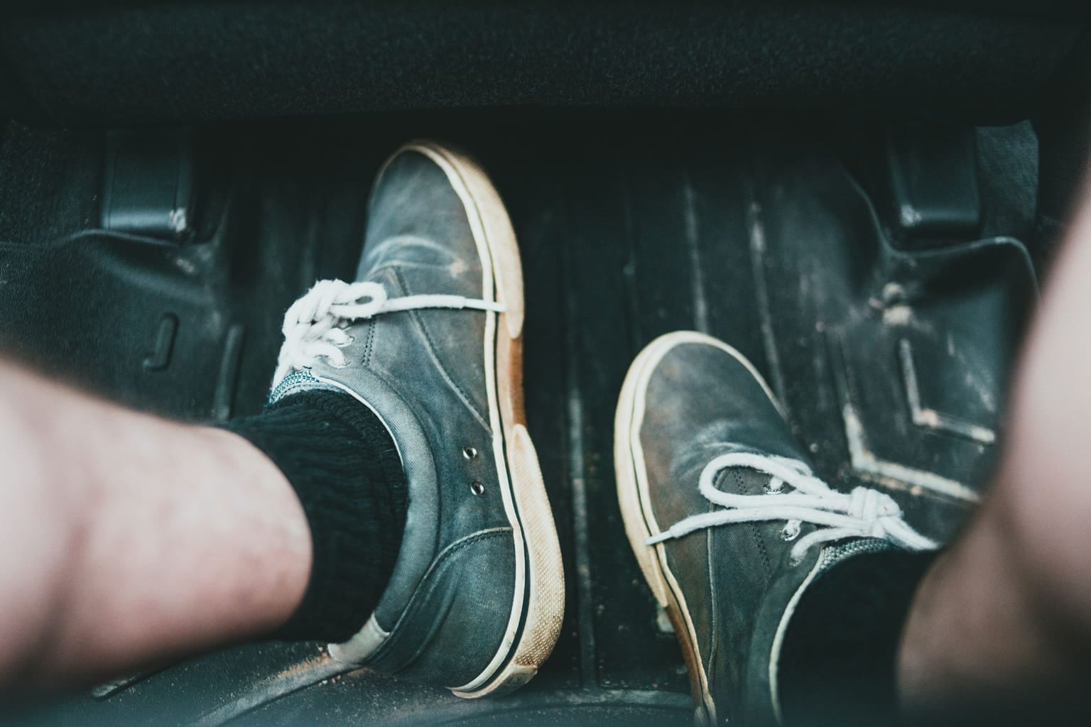 Driver's feet in a car footwell beside the pedals