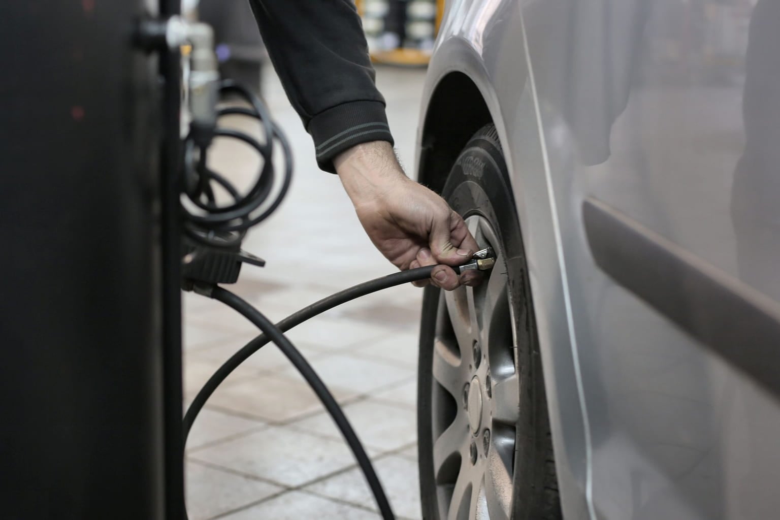 Mechanic inflating a car tire with an air hose and pressure gauge