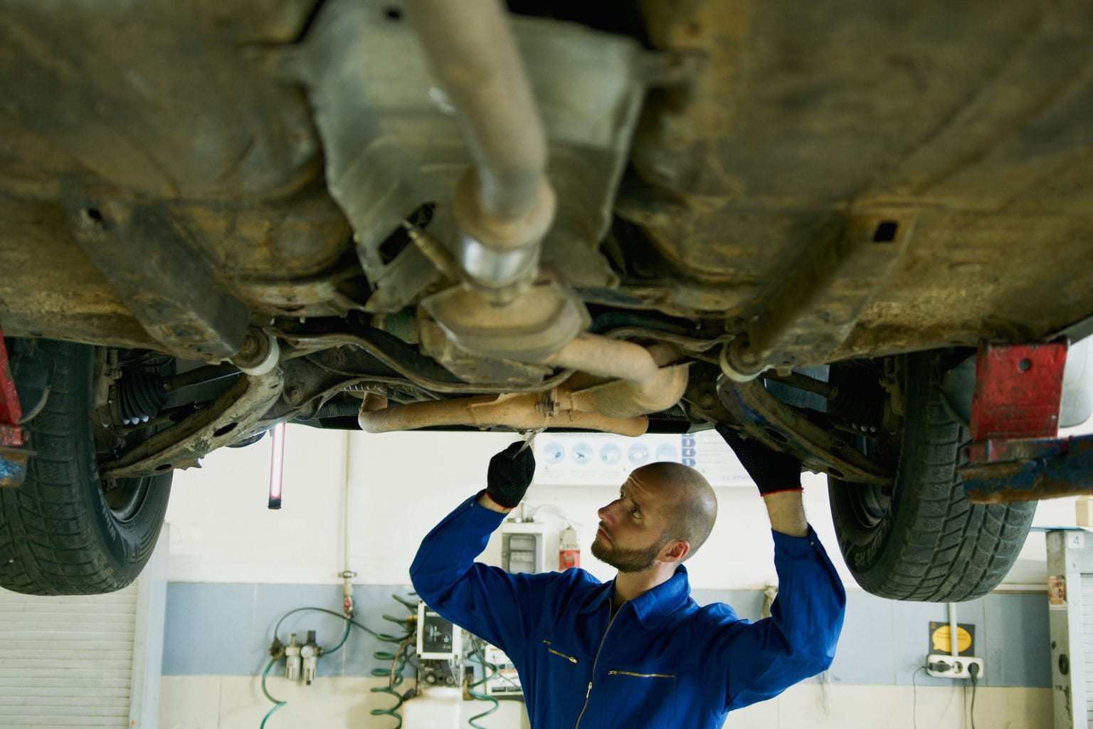 Mechanic inspecting the underside of a car raised on a lift