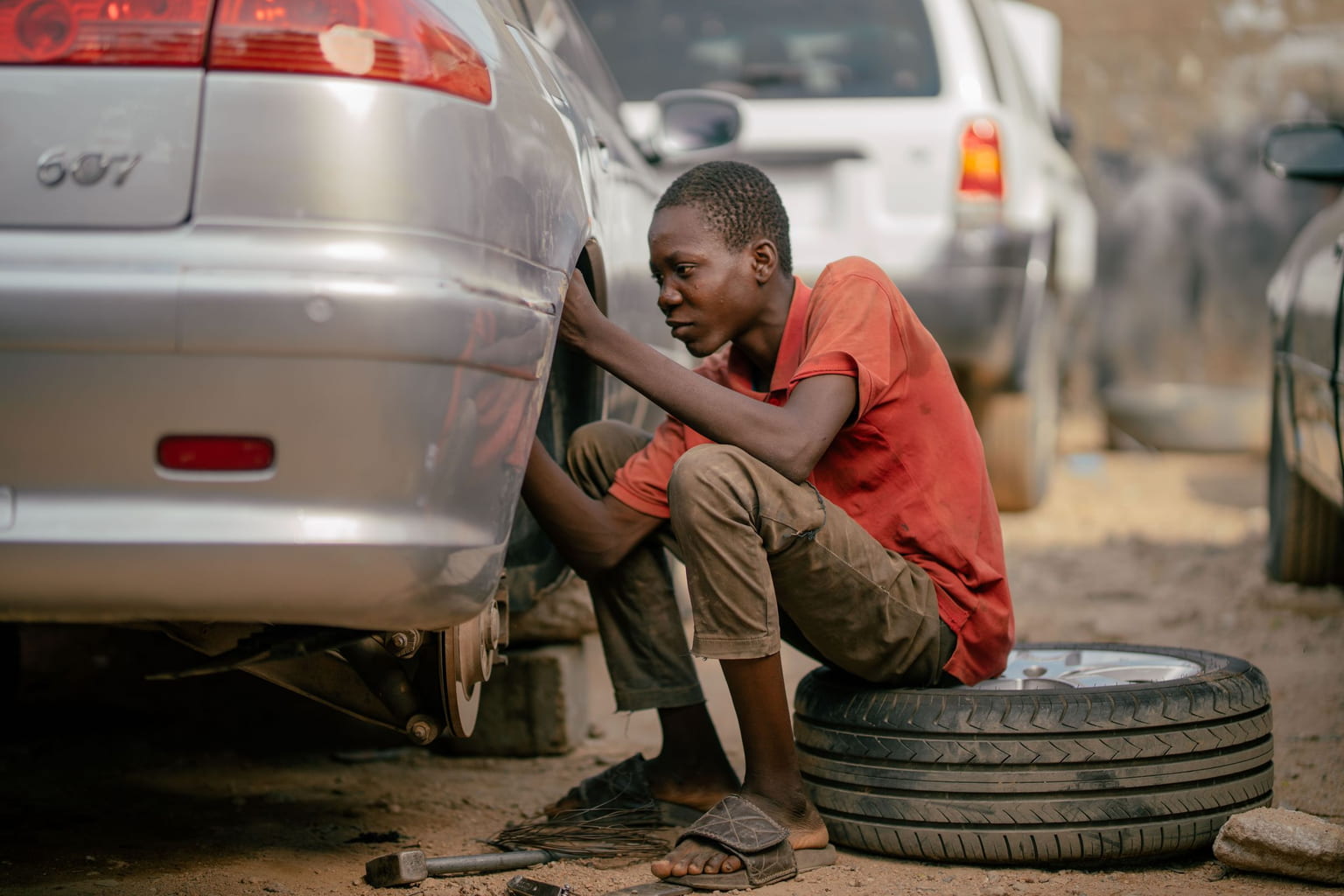Young mechanic working on a car's wheel beside a removed tire
