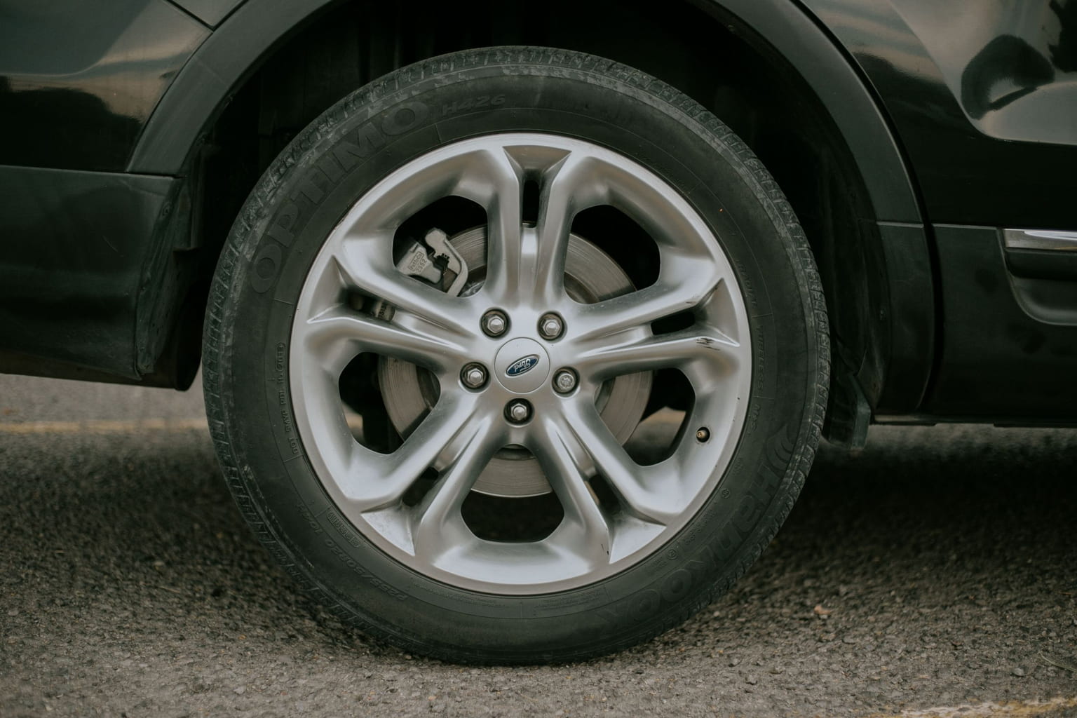 Alloy wheel and tire on a dark SUV, seen close to the ground
