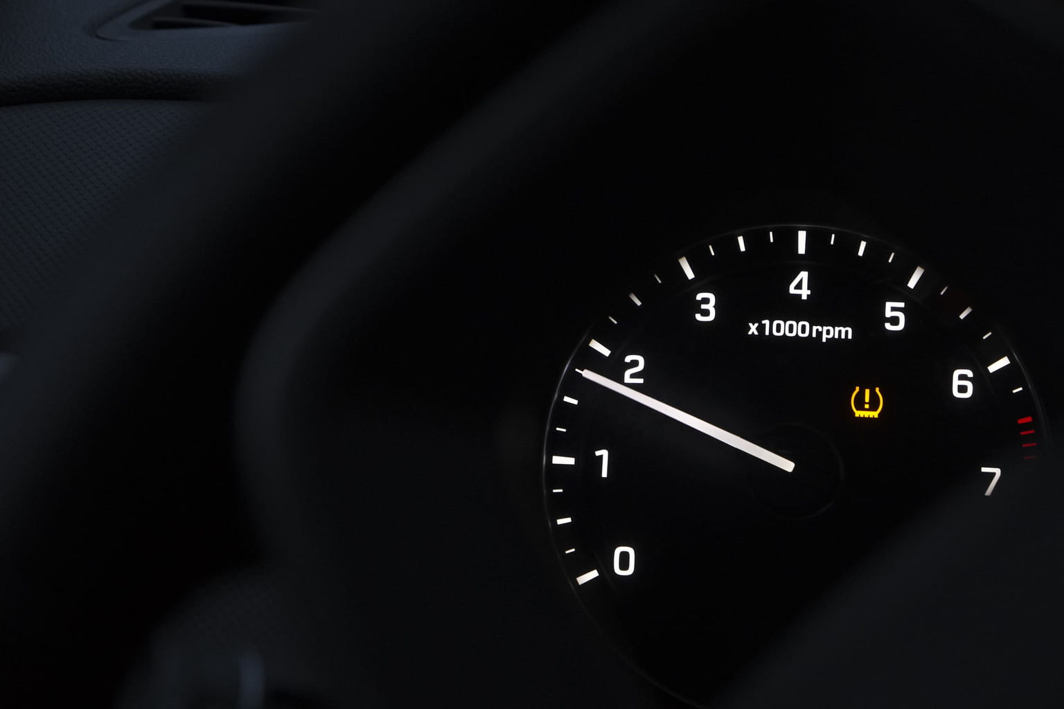 Amber tire pressure warning light glowing on a car's tachometer