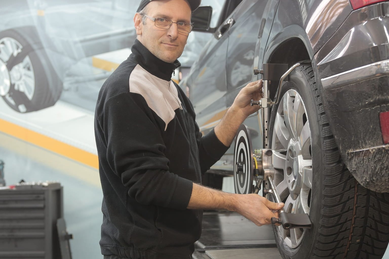 Mechanic fitting wheel alignment equipment to a car wheel