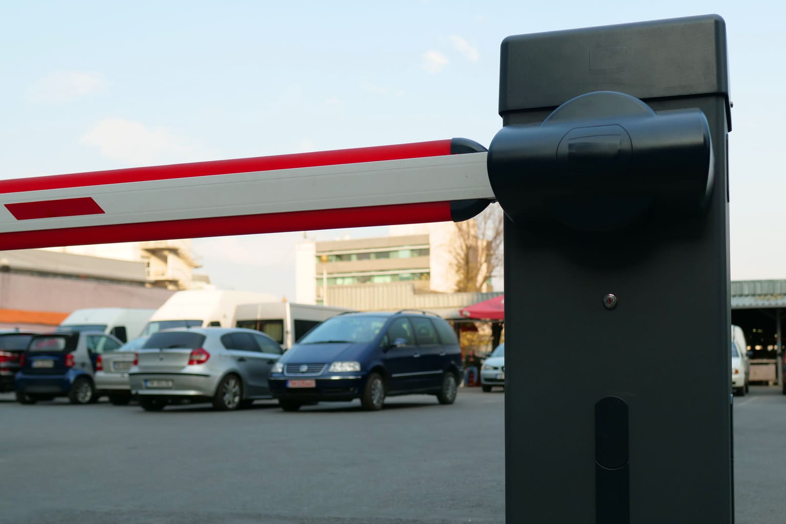 Red and white barrier arm at the entrance of an outdoor parking lot