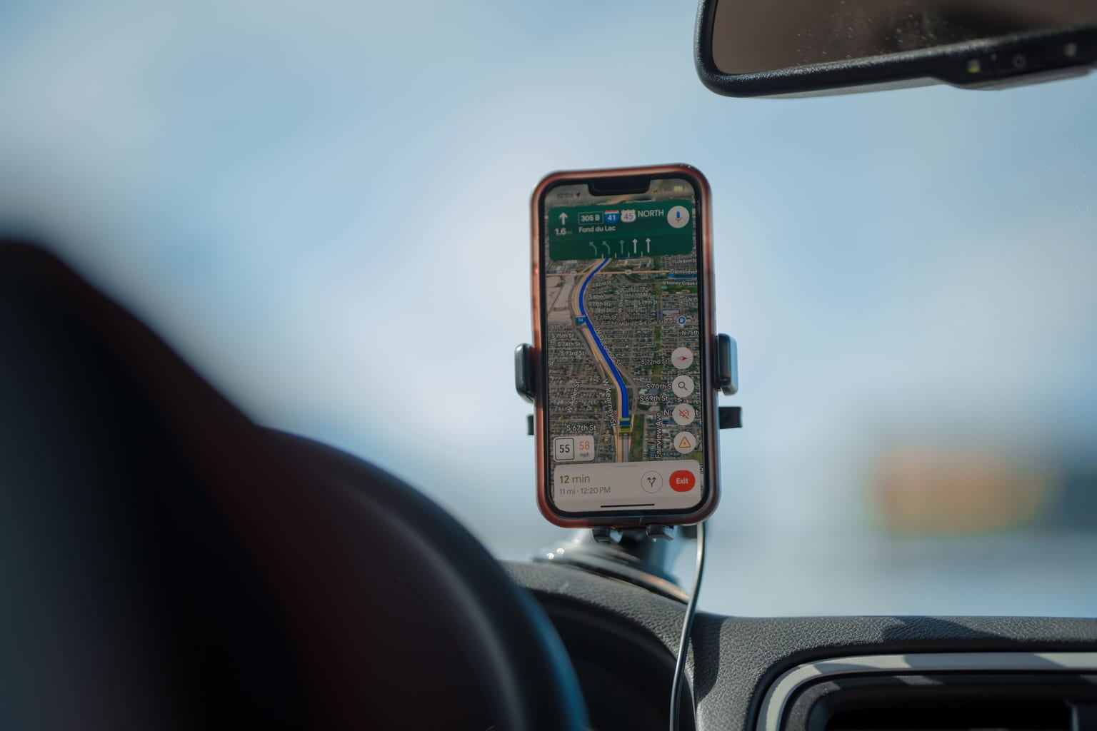 Smartphone showing a GPS navigation route, mounted on a car dashboard