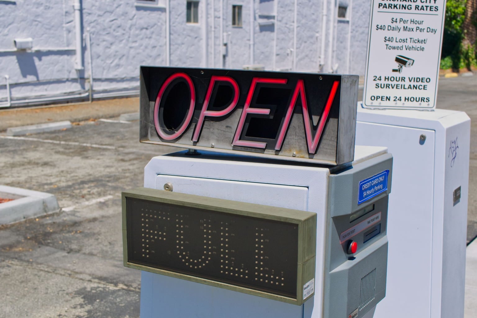 Parking lot entrance machine with an Open sign, a Full display and a posted rates board