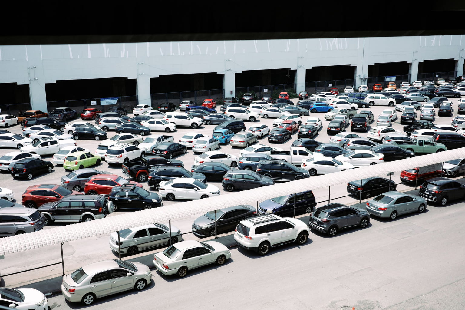 Rows of parked cars filling an open-air lot beside a multi-level parking structure