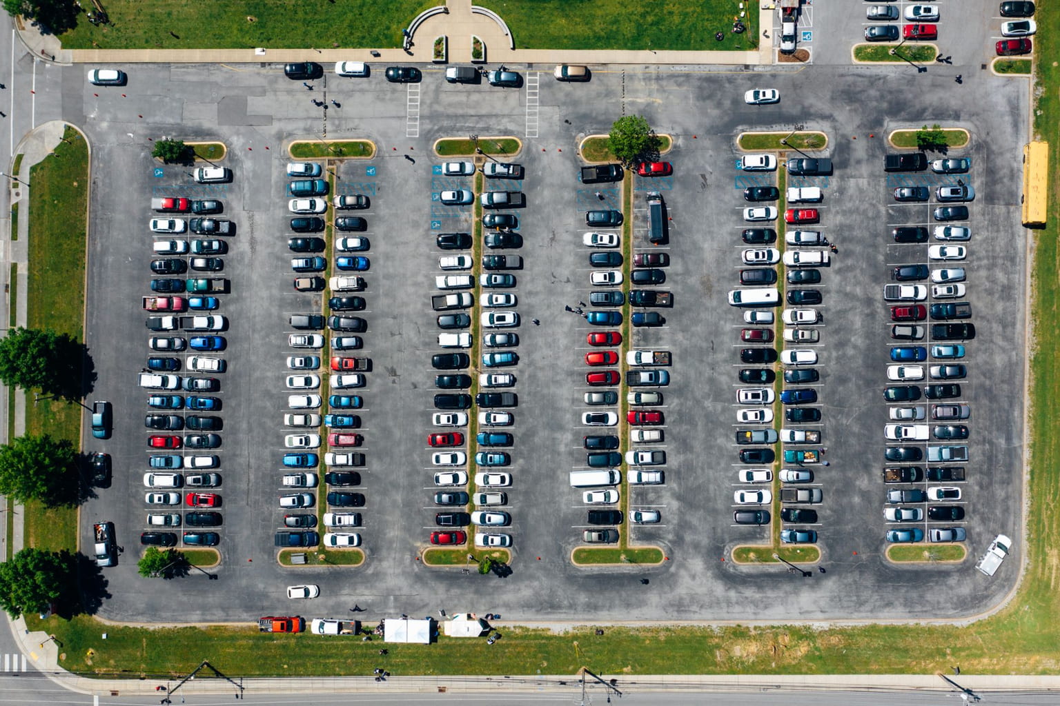 Aerial view of a large open-air parking lot lined with trees