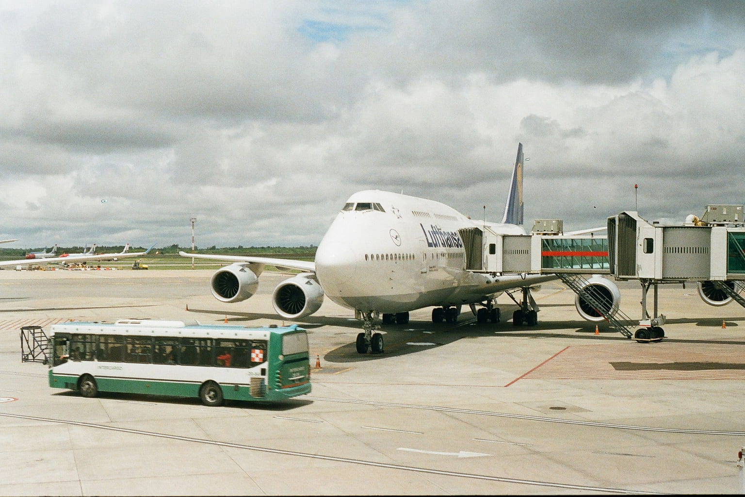 Passenger jet at an airport gate with a shuttle bus on the apron