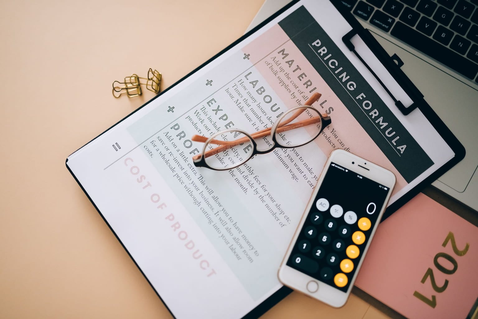 Smartphone calculator and glasses on a printed pricing worksheet